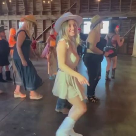 Sydney Sweeney is in her cowboy outfit dancing in room full of people.